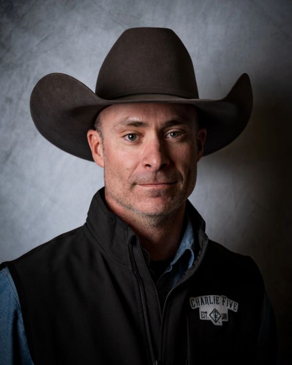 Man wearing a cowboy hat and black vest.
