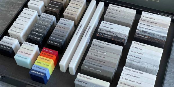 A variety of solid surface material samples organized in a box.