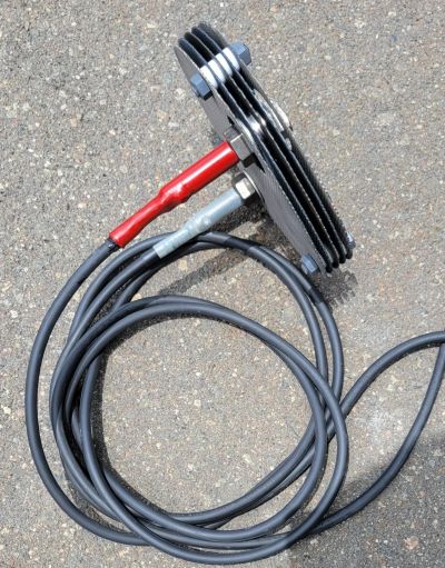 Metal sensor plate with attached cables on pavement.
