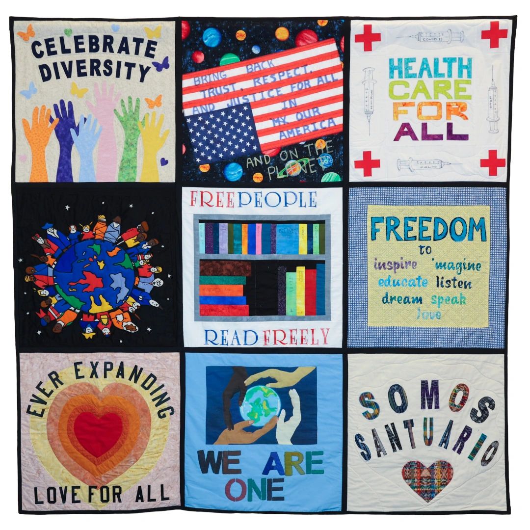 Quilt with messages of diversity, freedom, and unity in colorful panels.