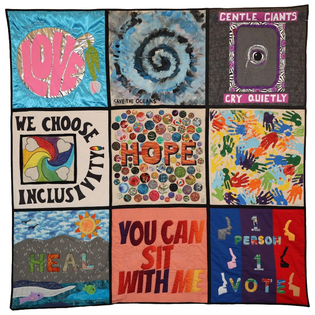 Quilt with nine colorful panels promoting love, hope, and inclusivity.