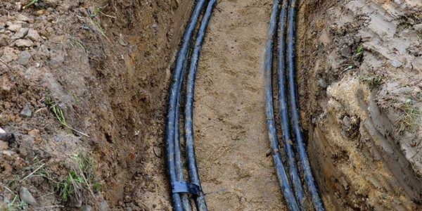 Trench with underground cables laid in sandy soil.