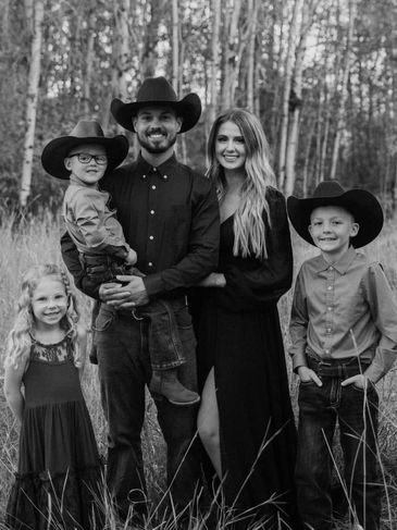 Family portrait with cowboy hats in a forested area.