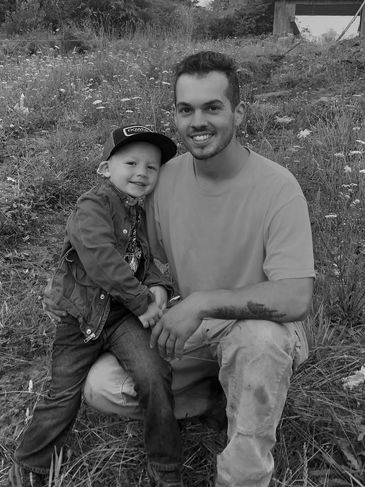 Man and boy outdoors smiling together.