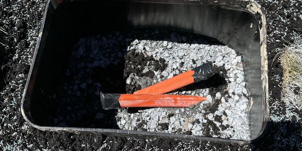A black container with gravel and two orange markers inside.