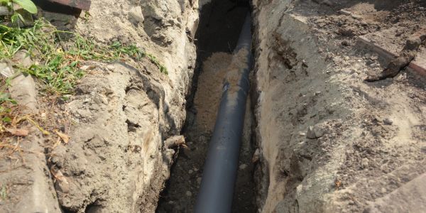 Black pipe being laid in a trench.
