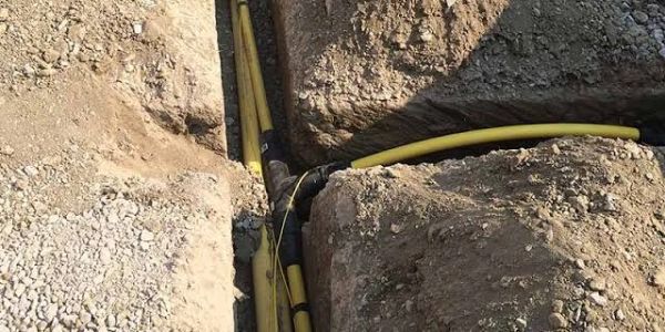 Yellow utility pipes buried in ground trenches.