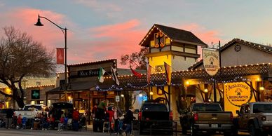 Evening gathering outside Auslander Biergarten with warm lights and parked trucks.