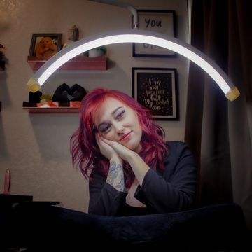 Woman with pink hair posing under a ring light.
