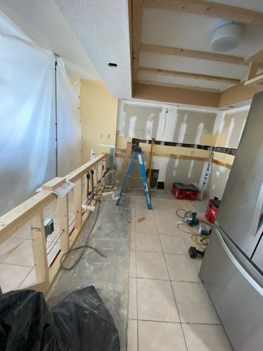 Kitchen under renovation with exposed framing and tools scattered.