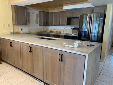 Modern kitchen with wooden cabinets, marble countertops, and stainless steel appliances.