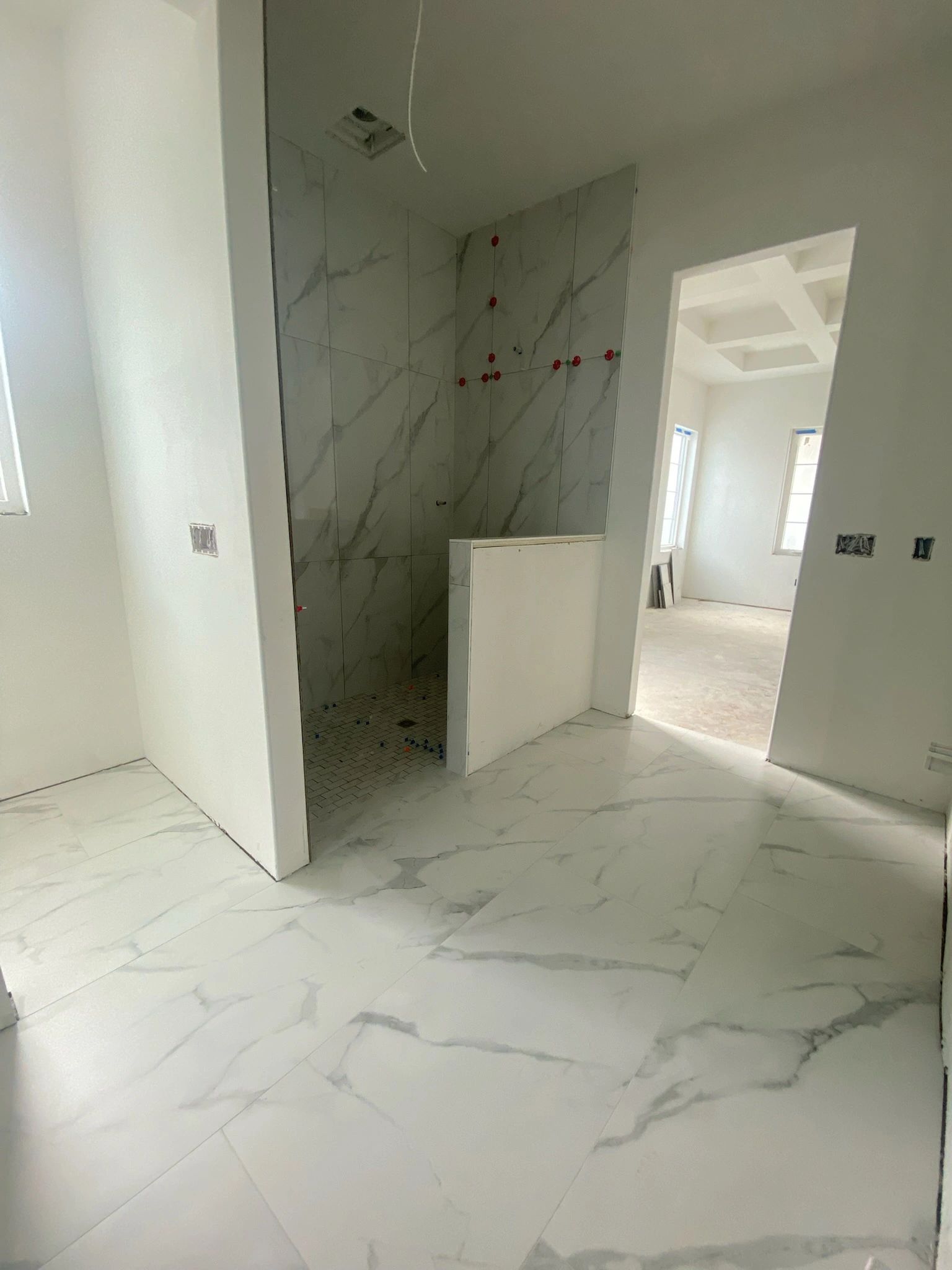 Under-construction bathroom with marble tiles and a partially tiled shower area.