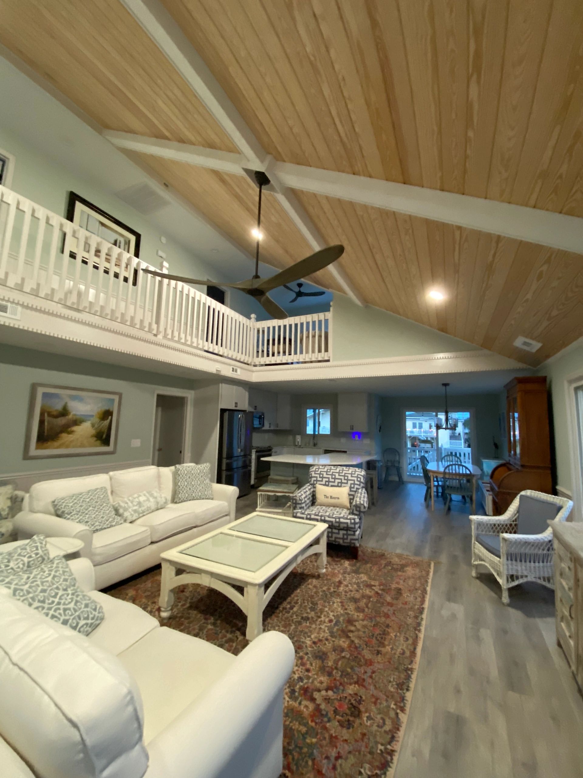 Cozy living room with vaulted wooden ceiling and open kitchen.