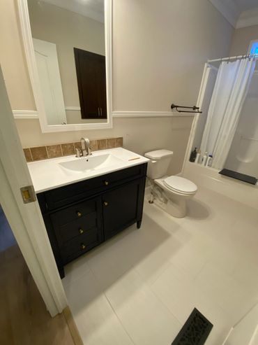 Clean bathroom with dark vanity, white fixtures, and a shower with curtain.
