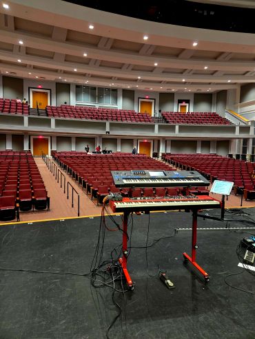 Music keyboards on stage facing empty auditorium.