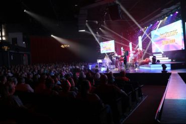 A live band performs on stage at a packed concert venue.