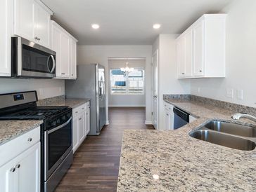 Modern kitchen with white cabinets and granite countertops.