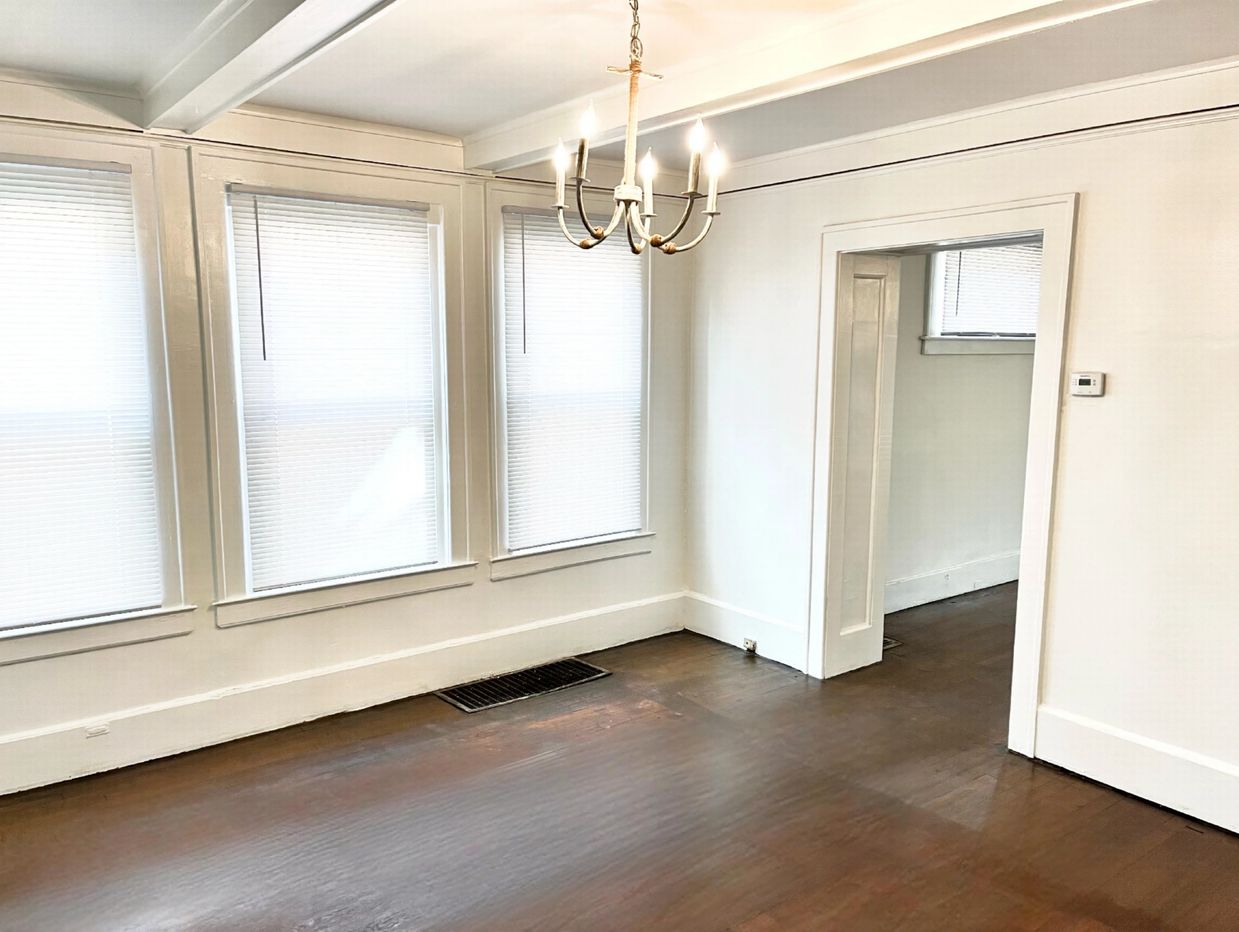 Bright empty room with hardwood floors and chandelier lighting.
