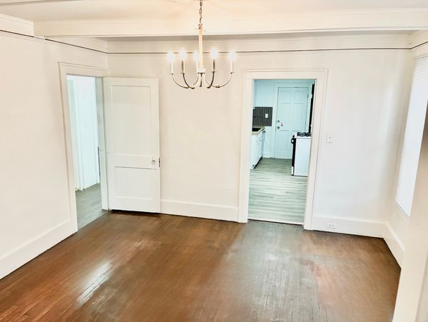 Empty room with wooden floor and chandelier lighting.