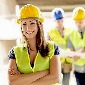 Smiling female construction worker with safety gear at site.