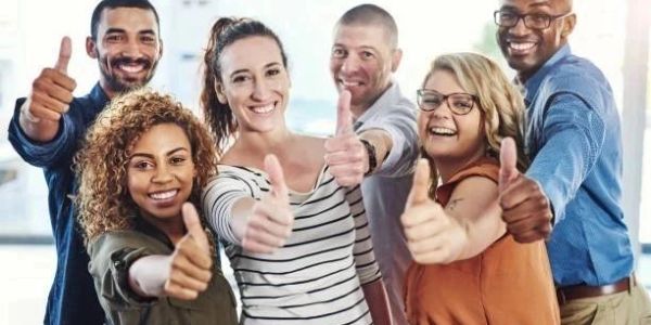 A diverse group of six people giving thumbs up and smiling.