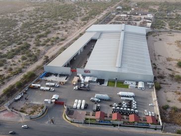 A person sitting at a desk, working on a laptop with books and a coffee cup nearby.