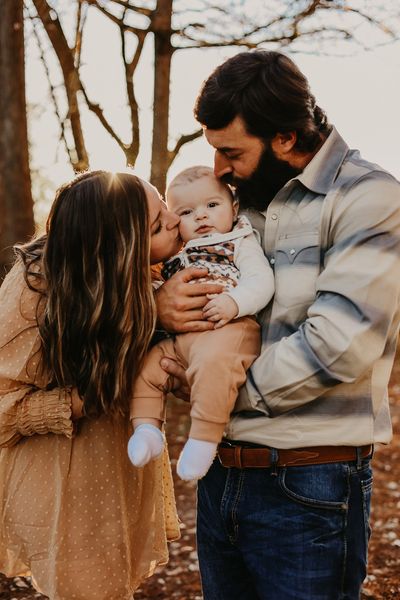 Happy family portrait: mom and dad holding and kissing their sons cheeks