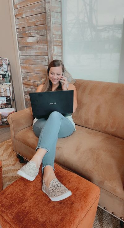 Laramy Schoen using her phone and laptop to help a client.