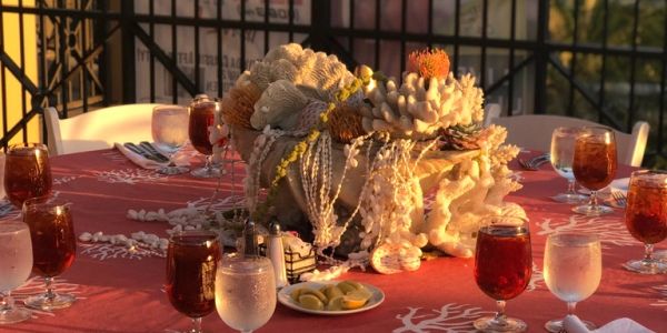 Elegant outdoor dining table with coral-themed decor and sunset glow.