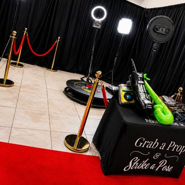 Photo booth setup with props, ring lights, and red carpet.