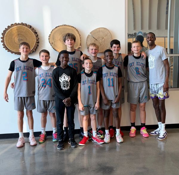 Youth basketball team posing indoors with coach and players in uniform.