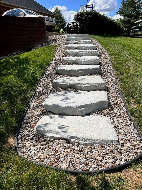 Stone pathway steps lined with small rocks in a grassy yard.