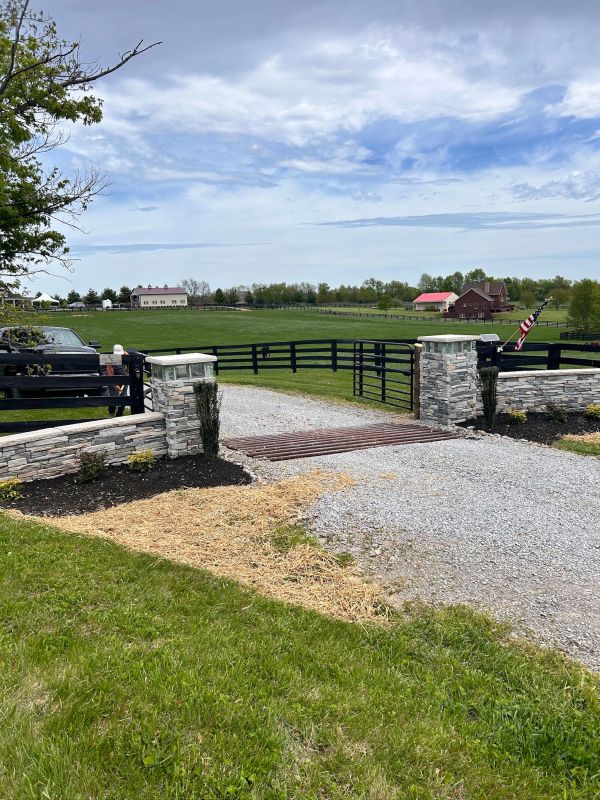 Scenic rural entrance with stone pillars and gravel road.