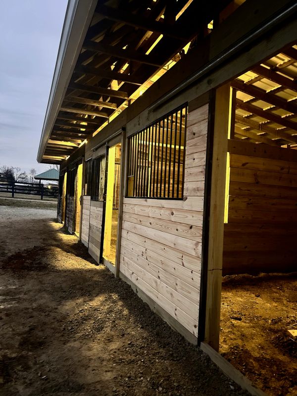 Wooden horse stable lit at dusk.