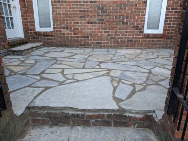 Stone patio with uneven patches and a small step.