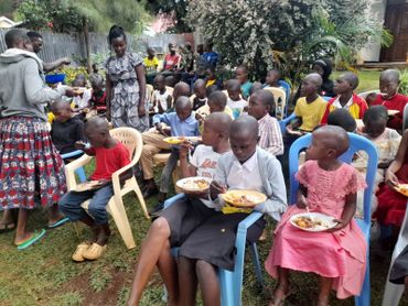 Children sitting outdoors enjoying a meal together.