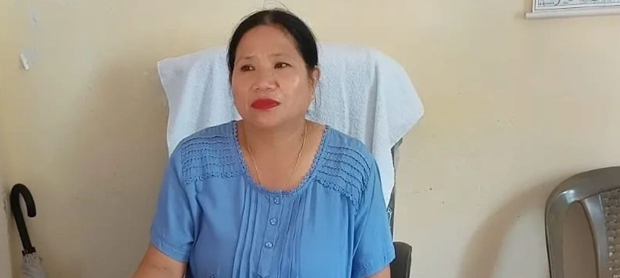 Woman sitting on a chair wearing a blue top.