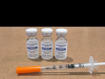 Three semaglutide medication vials with a syringe on a table.