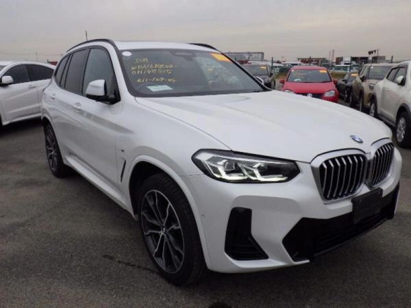 White BMW SUV parked in a lot with other vehicles.