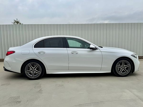 Sleek white luxury sedan parked beside a metallic fence.