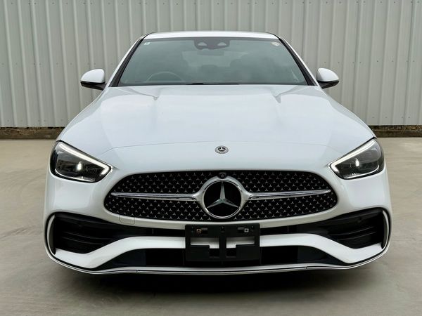 Front view of a white Mercedes-Benz car with sleek headlights and grille.
