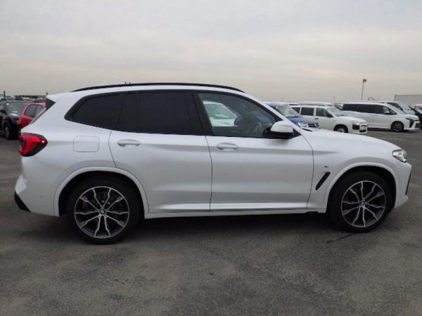 White luxury SUV parked in a lot on a cloudy day.