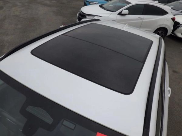 Close-up of a white car's sunroof with other cars in the background.