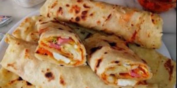 Plate of rolled flatbreads filled with eggs, vegetables, and possibly ham.