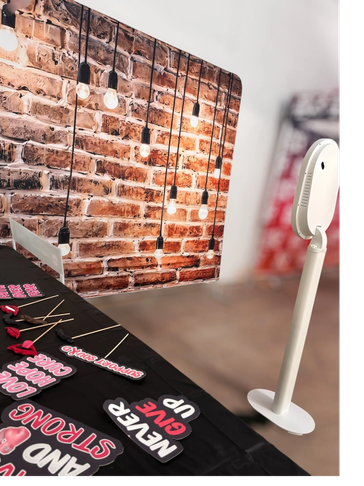 Photo booth setup with a brick wall backdrop and fun photo props.