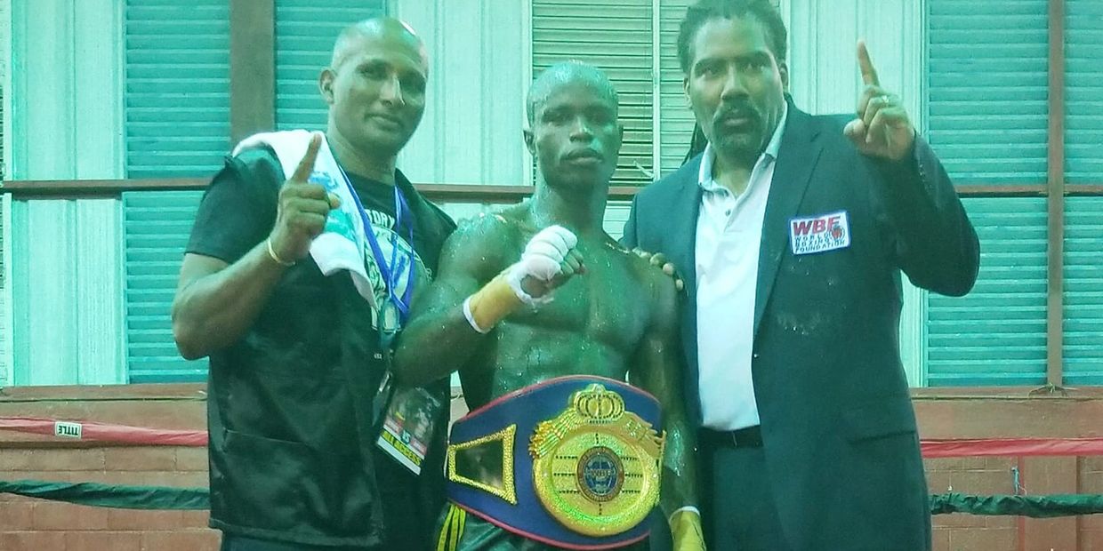 Prince-Lee Isidore posing with his WBF championship belt with his coach and WBF representative