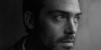 Black and white close-up of a man looking thoughtfully to the side.
