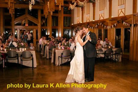 Bride and Groom enjoy First Dance together at reception as wedding guests look on