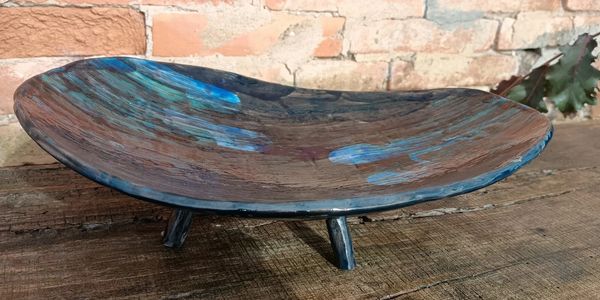 Handcrafted ceramic dish with blue and brown glaze on three small legs.
