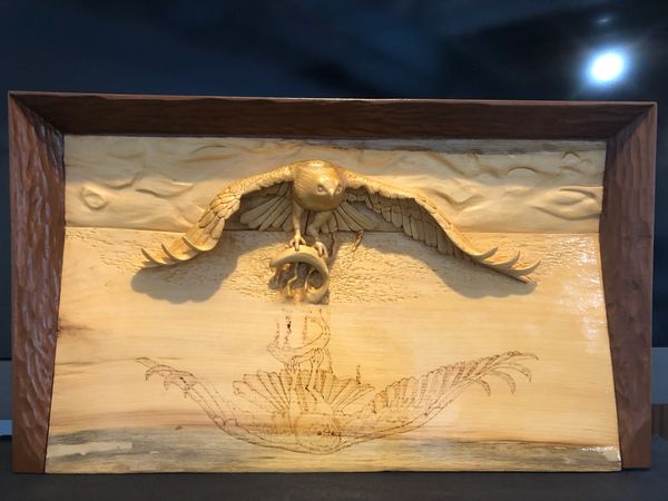 This wood carving depicts an Osprey coming out of the water with it's prey.